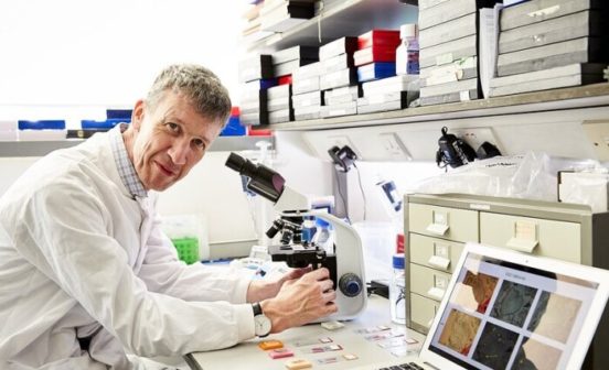 Professor Iain McNeish leaning across his work desk